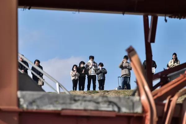 Les gens prient alors qu'ils participent à une minute de silence pour se souvenir des victimes du 14e anniversaire du tremblement de terre, du tsunami et de la catastrophe nucléaire de 2011. Photo de Str / Jiji Press / AFP via Getty Images.